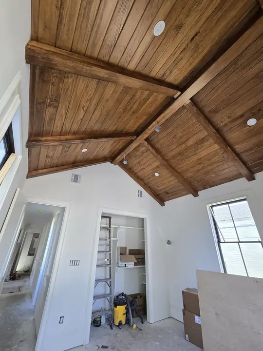 Vaulted bedroom ceiling with stained wood beams and tongue-and-groove boards