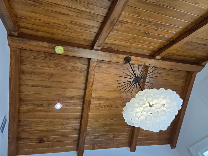 Vaulted wood ceiling with exposed beams and a statement chandelier